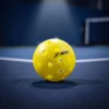 Gros plan des 40 trous d'une balle de pickleball outdoor sur terrain bleu