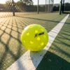 Balle de pickleball outdoor posée sur la ligne d'un terrain extérieur